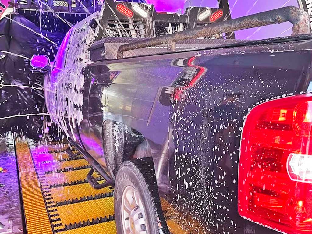 Black truck going through a Modbrite tunnel car wash